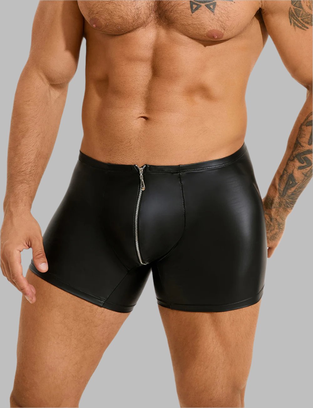 a man in black leather shorts with a tattoo on his arm