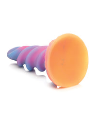 a pink, blue, and purple swirling unicorn horn dildo lying on its side with its orange suction cup base facing the camera by creature cocks