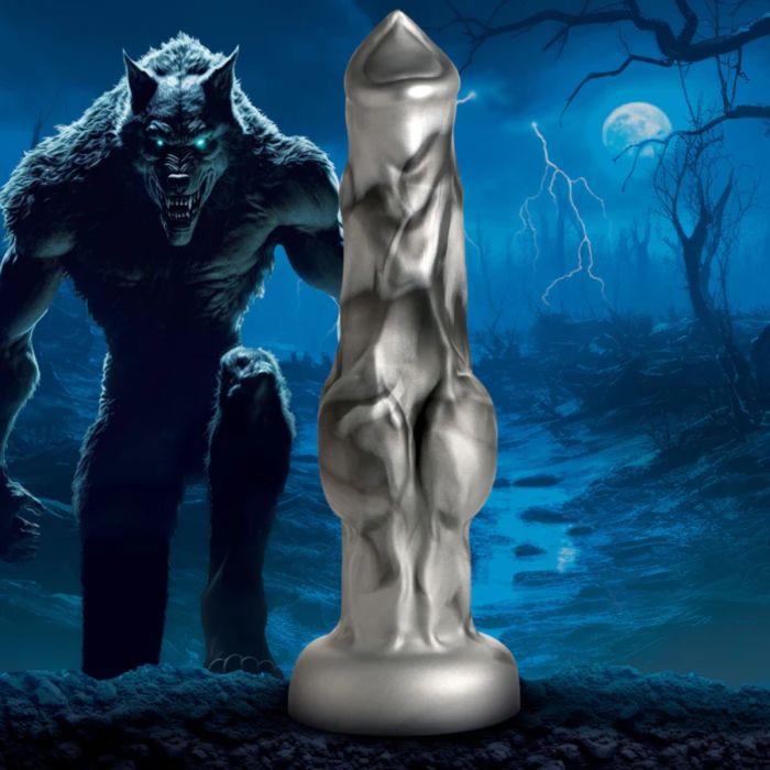 a silver statue of a monster next to a candle