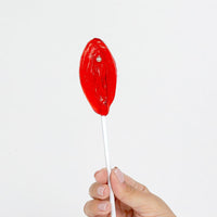 a person holding a red lollipop in their hand