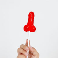 a person holding a red lollipop in their hand