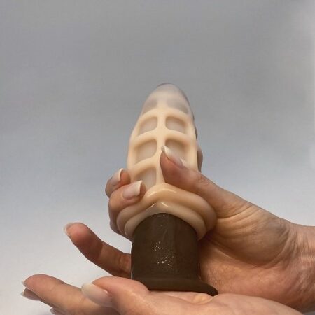 a woman's manicured hand hand holding a dildo with masturbator on top