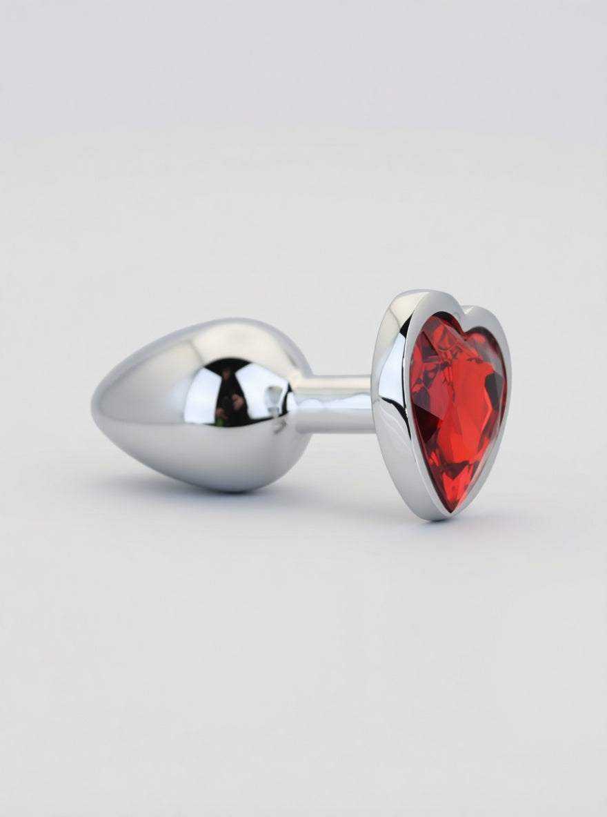 Toosh heart-shaped metal butt plug with red stone, available in small, medium, and large sizes, shown in the image.