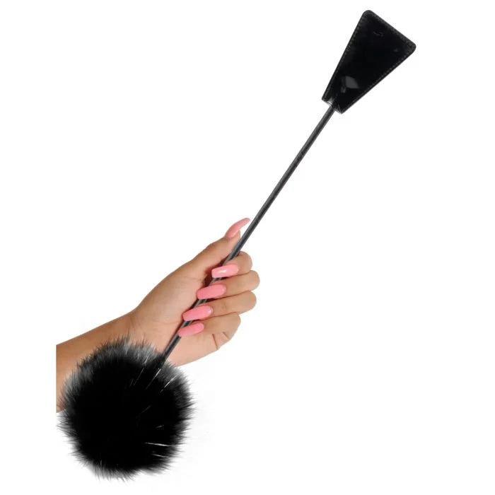 a woman's hand holding a black and white pom - pom