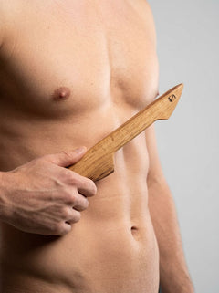 Handcrafted Barrel of Pain BDSM double-ended wooden wax play scraper made from whisky barrel oak with carved details.