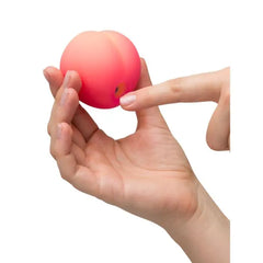 Romp Pink Peach silicone clitoral vibrator with suction function, compact design, and textured surface for targeted pleasure.