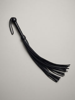 Artistic display of the Prowler RED Hard Whip - 34 Inch Leather BDSM Impact Flogger illustrating the supple leather and its suitability for sophisticated BDSM play.