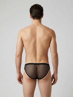 Man wearing black fishnet underwear against a plain background