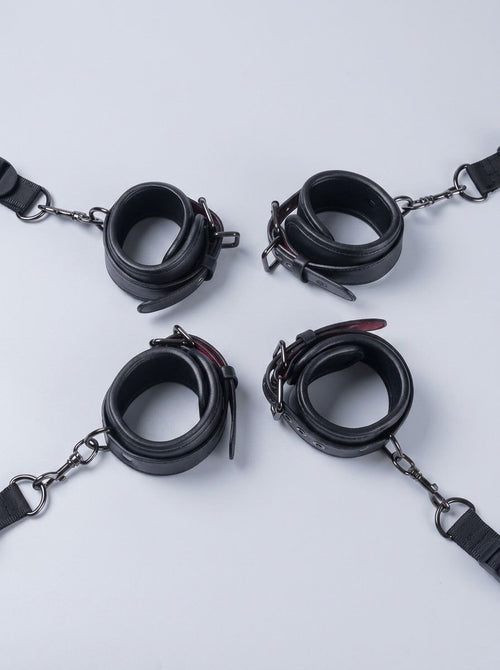 Luxury Faux Leather Bondage Bed Restraint Kit featuring four black adjustable cuffs with chains and straps, bed restraint accessories
