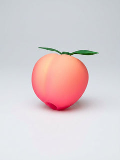 Romp Pink Peach silicone clitoral suction vibrator with textured tip and smooth body for pleasurable stimulation.